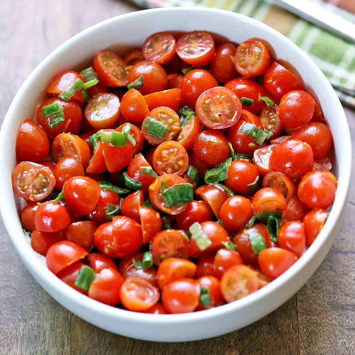 Tomato salad is served in a white bowl.