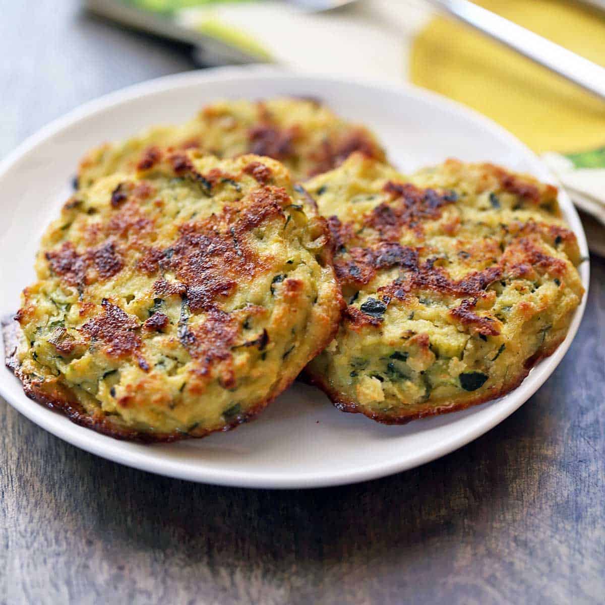 Zucchini fritters served on a white plate.