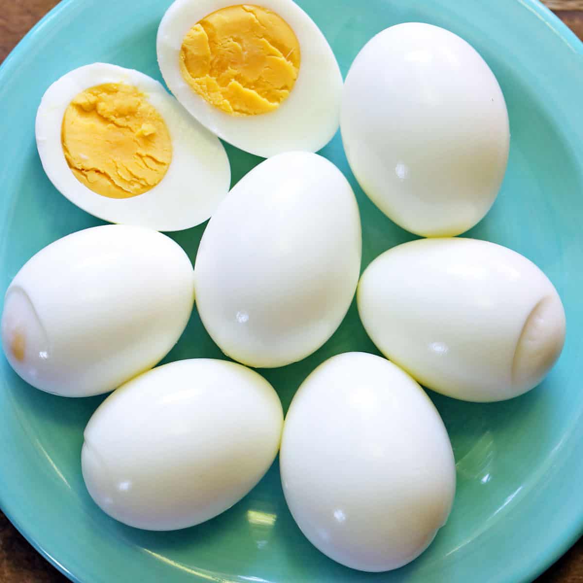 Hard-boiled eggs served on a turquoise plate.