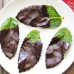 Chocolate mint leaves served on a white plate with a napkin.
