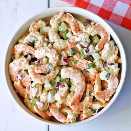 Shrimp salad served in a white bowl with a napkin.