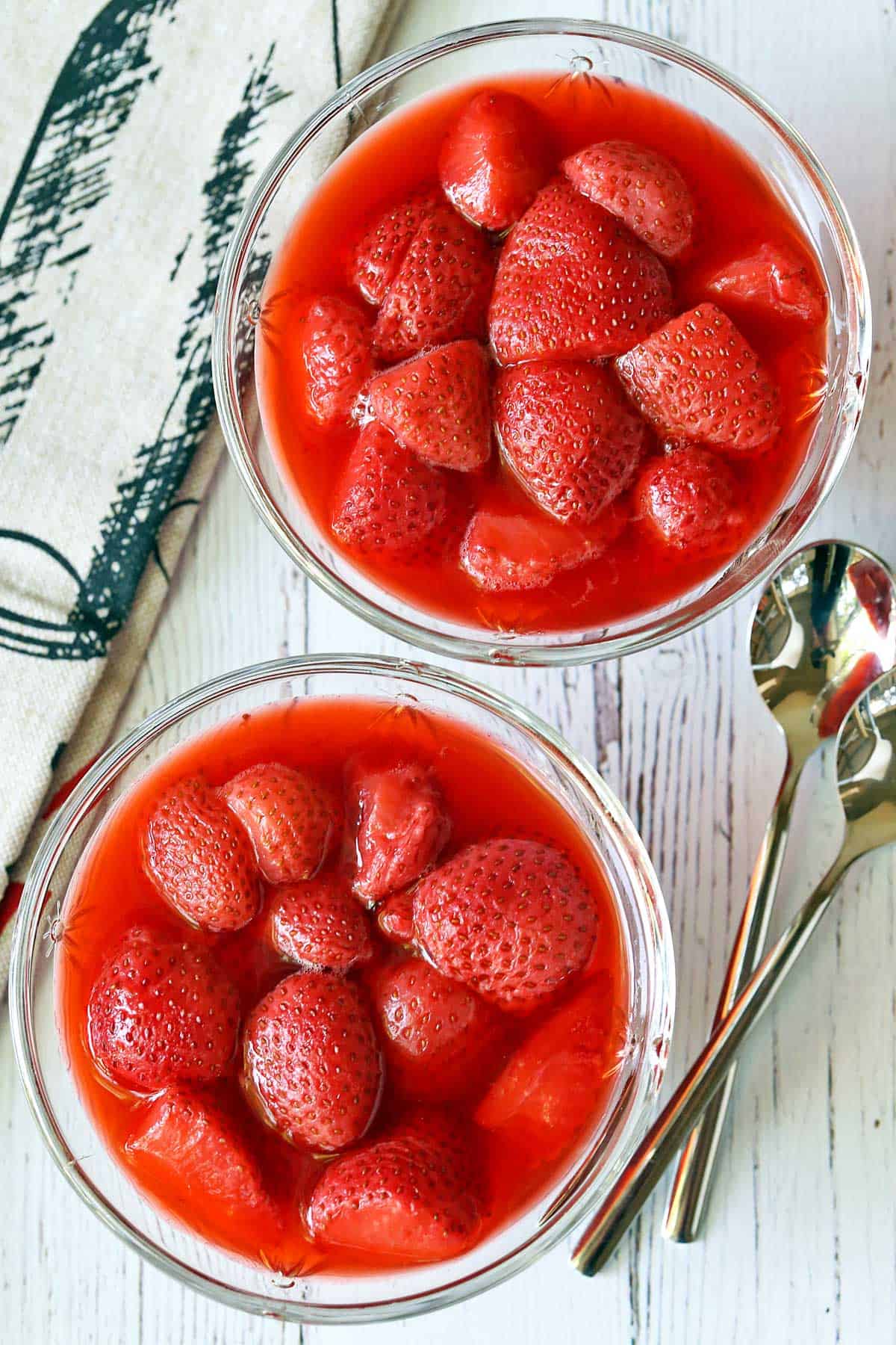 Strawberry compote served in dessert glasses with two teaspoons. 
