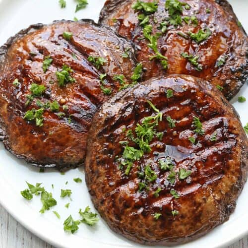 Grilled portobello mushrooms served on a white plate.