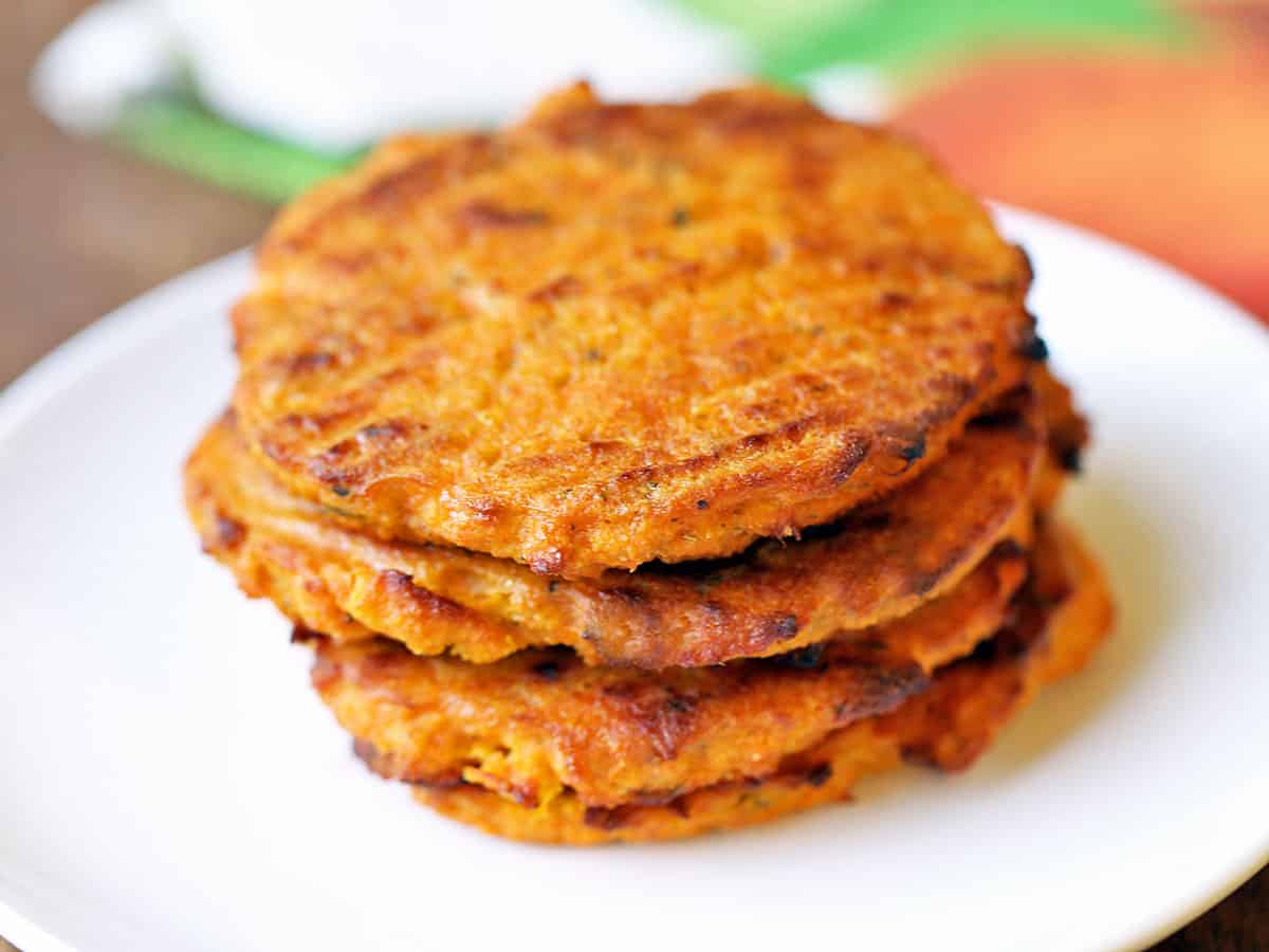 Sweet potato patties stacked on a white plate.