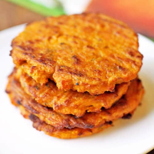 Sweet potato patties stacked on a white plate.