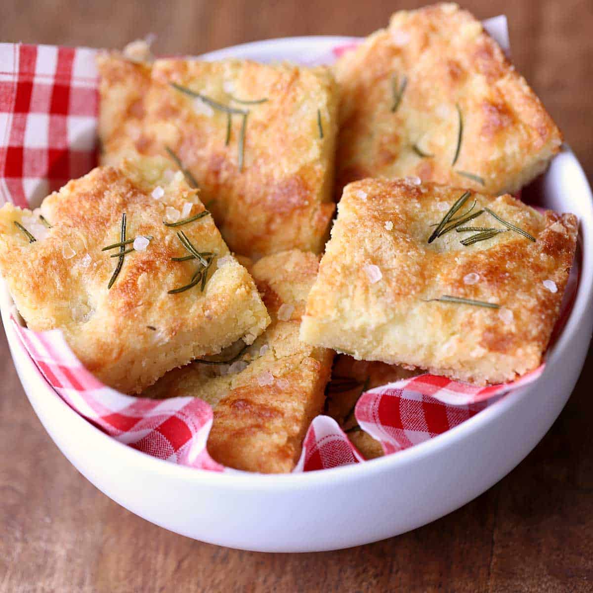 Keto focaccia served in a white bowl lined with a red checkered napkin.