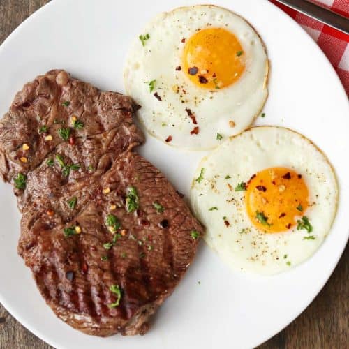 Steak and eggs served on a white plate.