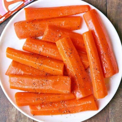 Steamed carrots served on a white plate.