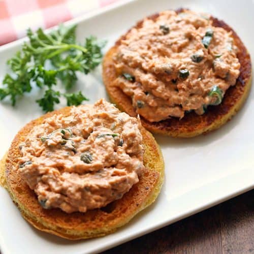 Salmon salad served on bread slices with parsley for garnish.