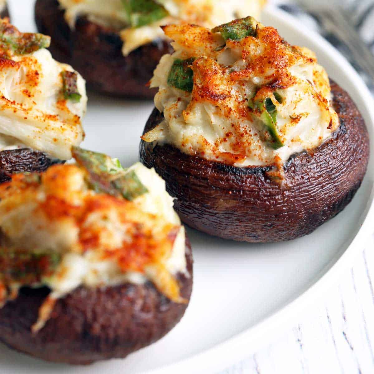 Crab-stuffed mushrooms served on a white plate.