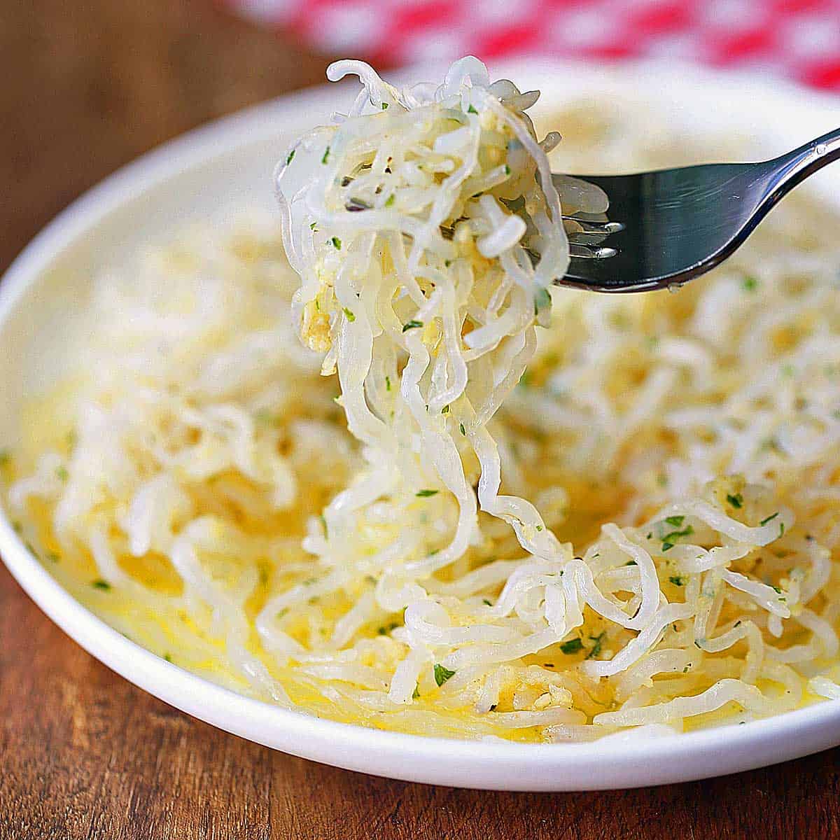 Shirataki noodles are served on a white plate with a fork.