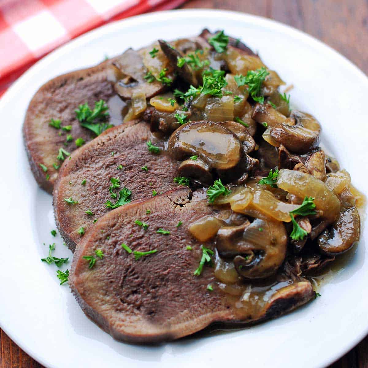 Beef tongue slices topped with onions and mushrooms.