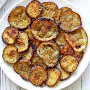 Eggplant chips piled on a white plate.