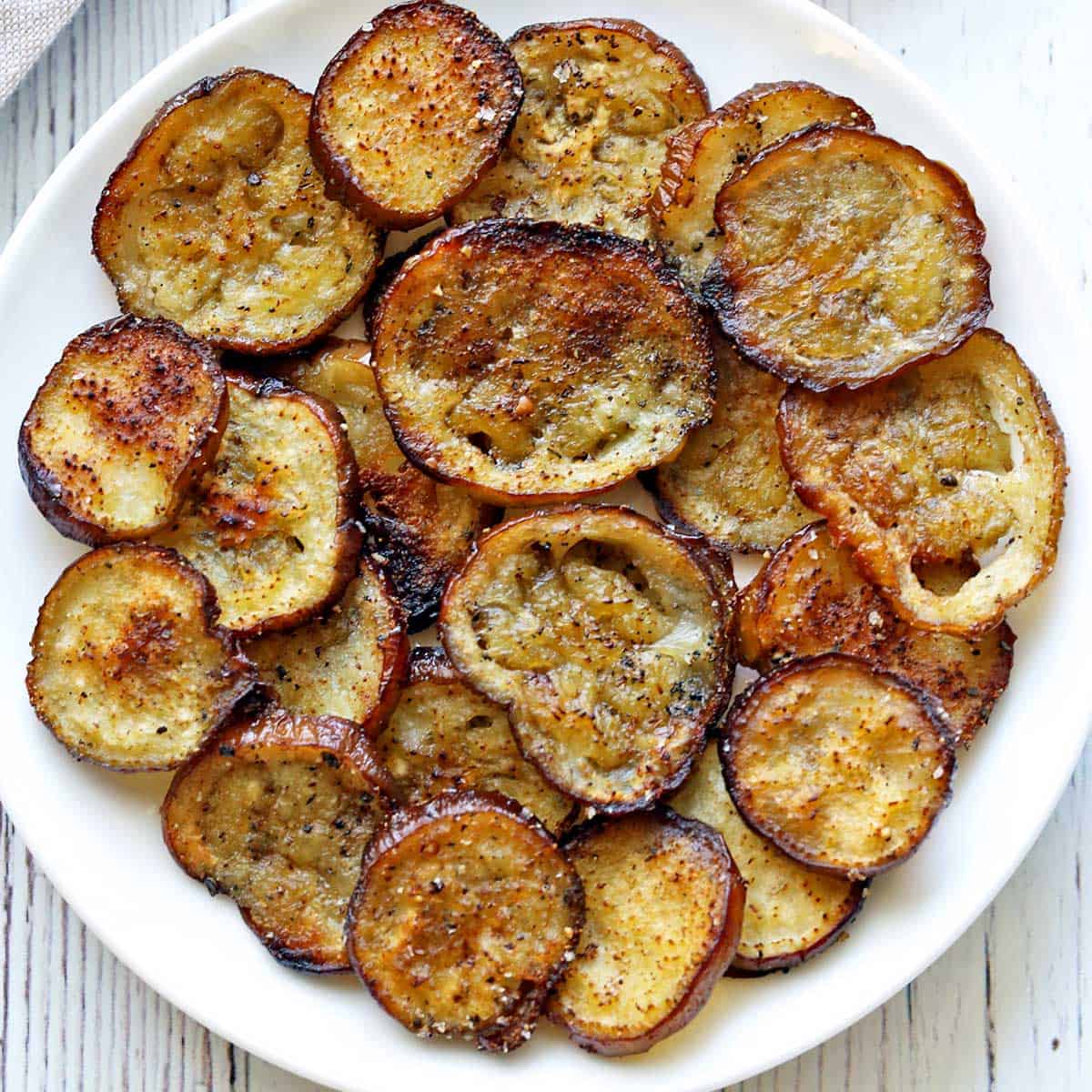 Eggplant chips piled on a white plate.