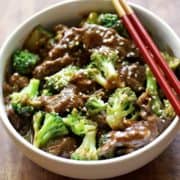 Beef and broccoli served with chopsticks.