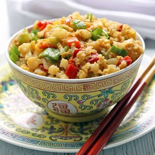 Cauliflower fried rice is served in a Chinese-style bowl with chopsticks.