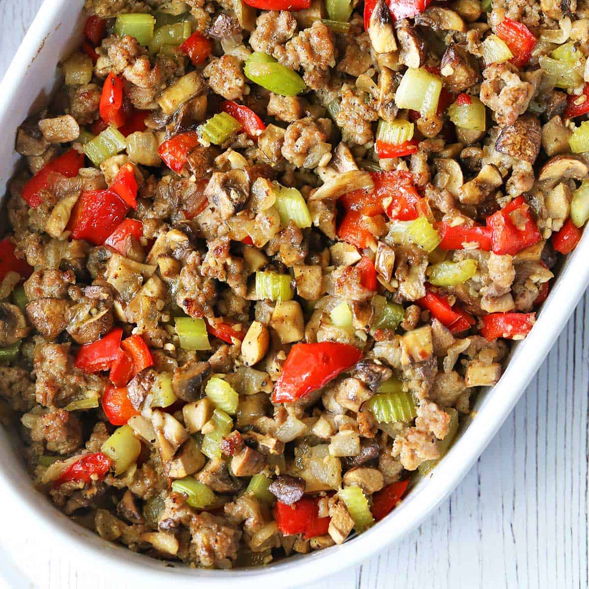 Sausage stuffing served in a white oval baking dish.