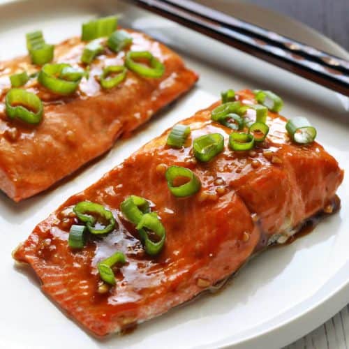 Asian salmon served on a white plate with chopsticks.