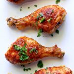 Buffalo chicken drumsticks topped with chopped parsley.