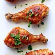 Buffalo chicken drumsticks topped with chopped parsley.