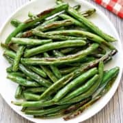 Roasted green beans served on a white plate with a napkin.
