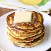 Keto ricotta pancakes stacked on a white plate, topped with butter.