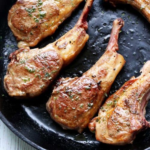 Lamb chops in a cast-iron skillet.