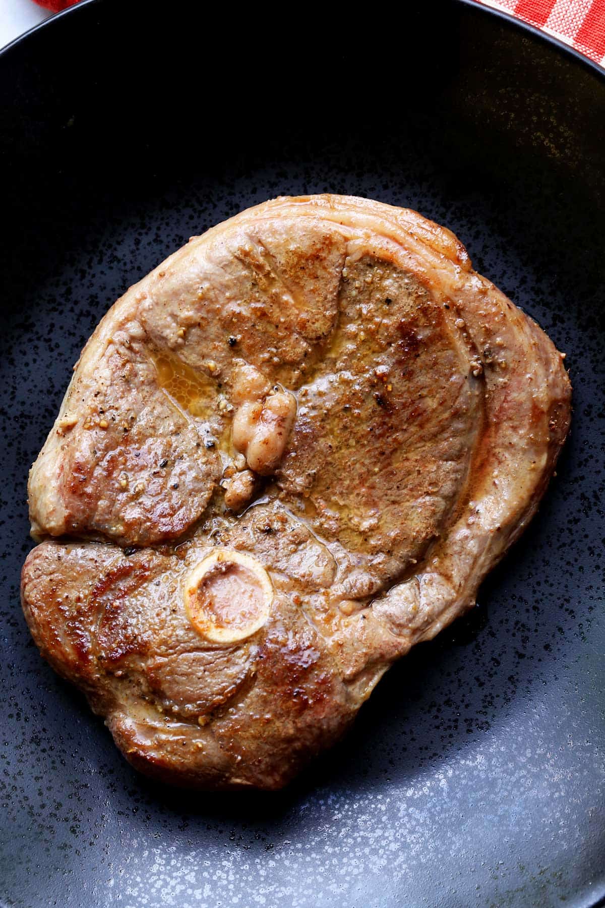 Lamb steak served on a dark plate.