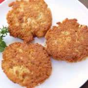 Chicken patties served on a white plate with parsley for garnish.