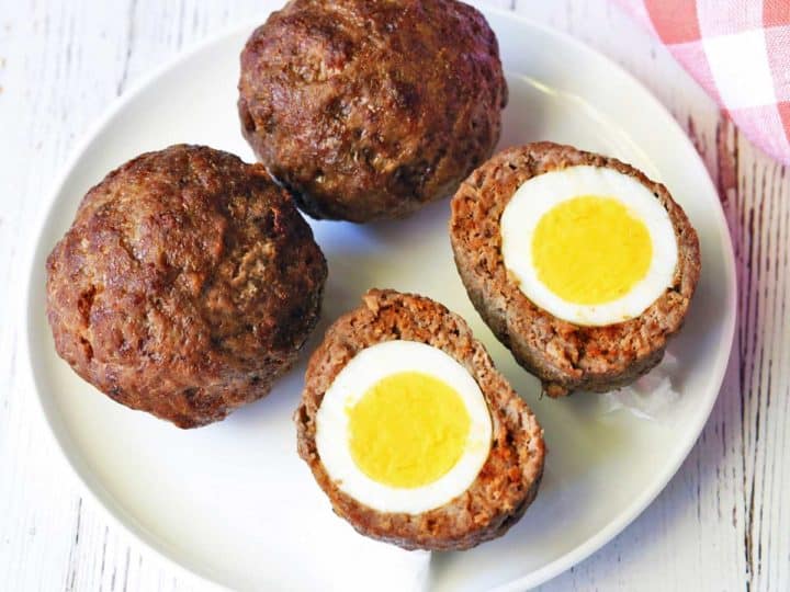Scotch Eggs served on a white plate with a napkin. 