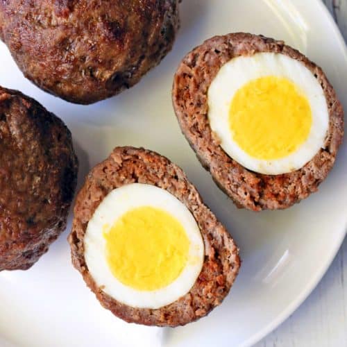 Scotch eggs served on a white plate.