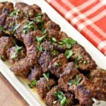 Beef kabobs are topped with chopped parsley.
