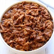 Slow cooker pulled pork served in a white bowl.