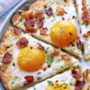 Keto breakfast pizza topped with eggs and bacon.
