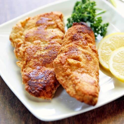 Keto fried fish served with lemon slices and parsley.