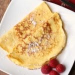 Keto crepes are served on a white plate with a garnish of berries.