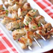 Oven-baked chicken kabobs served on a white platter.