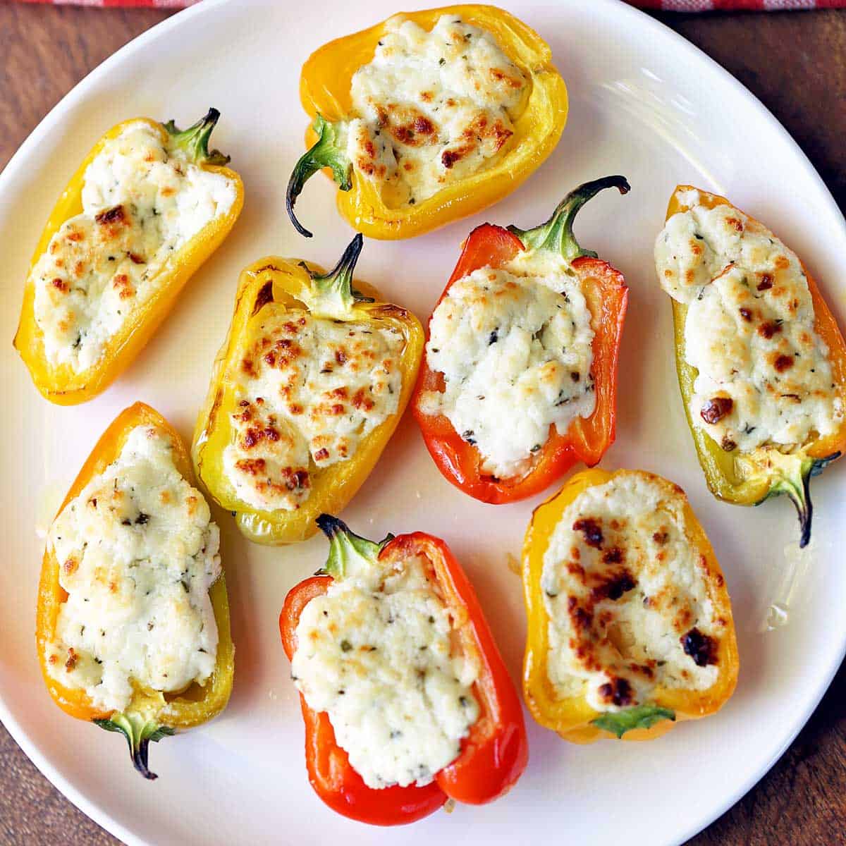 Stuffed mini peppers served on a white plate.