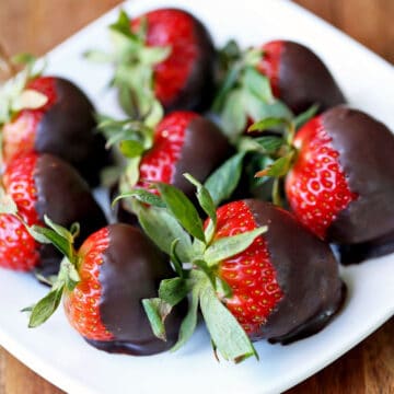 Chocolate-covered strawberries on a white plate.