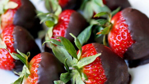 Chocolate-covered strawberries are served on a white plate.