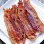 Microwave bacon is served on a plate lined with paper towels.