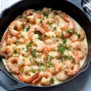 Shrimp in cream sauce served in a cast-iron skillet.