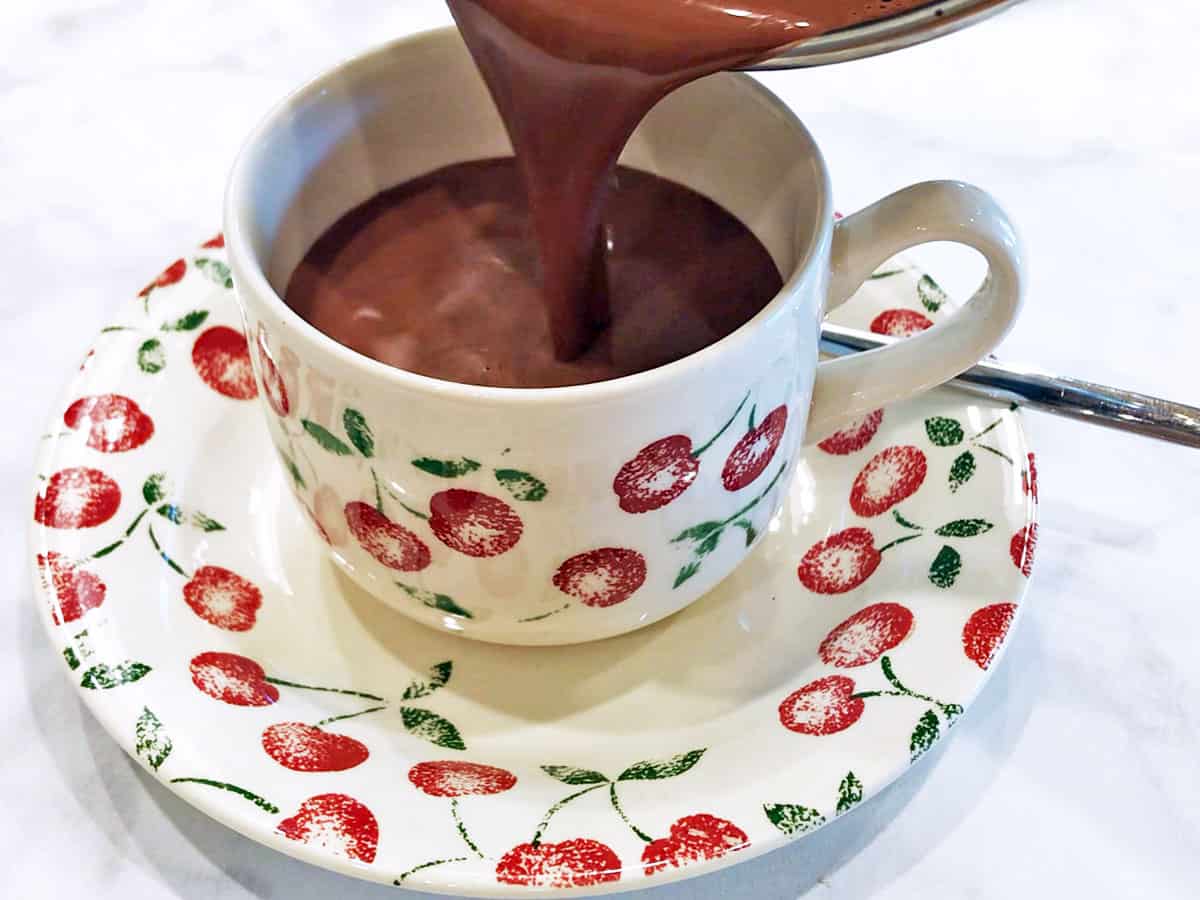 Pouring keto hot chocolate into a cup.