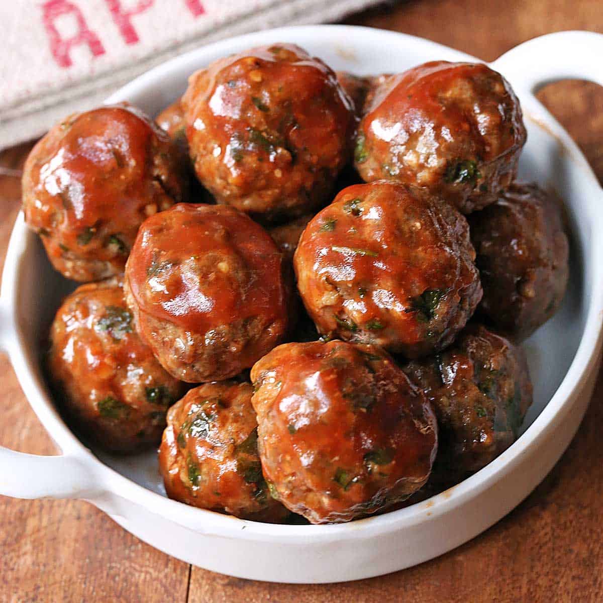 Glazed keto meatballs are served in a white bowl.