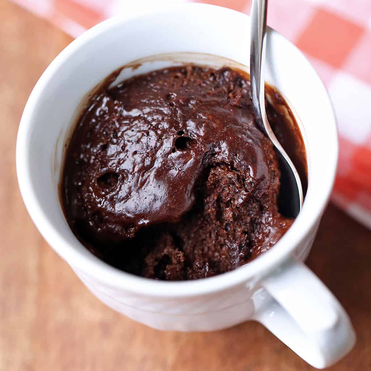 Keto chocolate mug cake served in a white mug with a spoon.