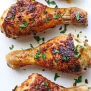 Baked chicken drumsticks served on a white plate.