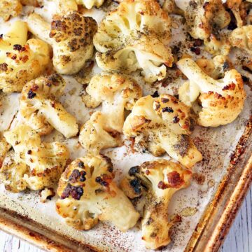 Roasted frozen cauliflower on a parchment-lined baking sheet.