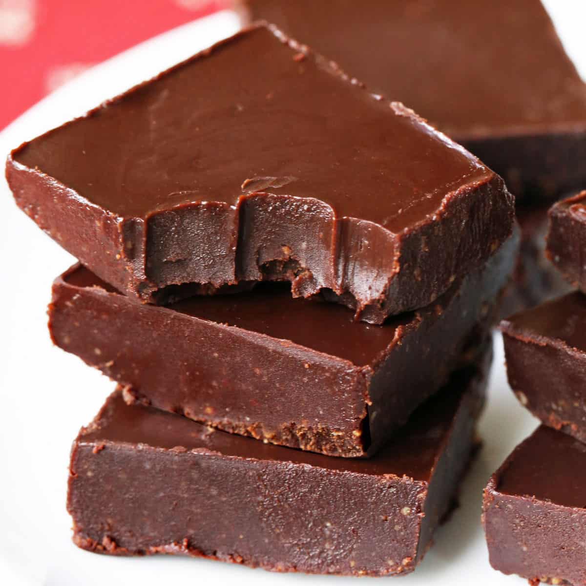 Keto fudge squares stacked on a white plate.