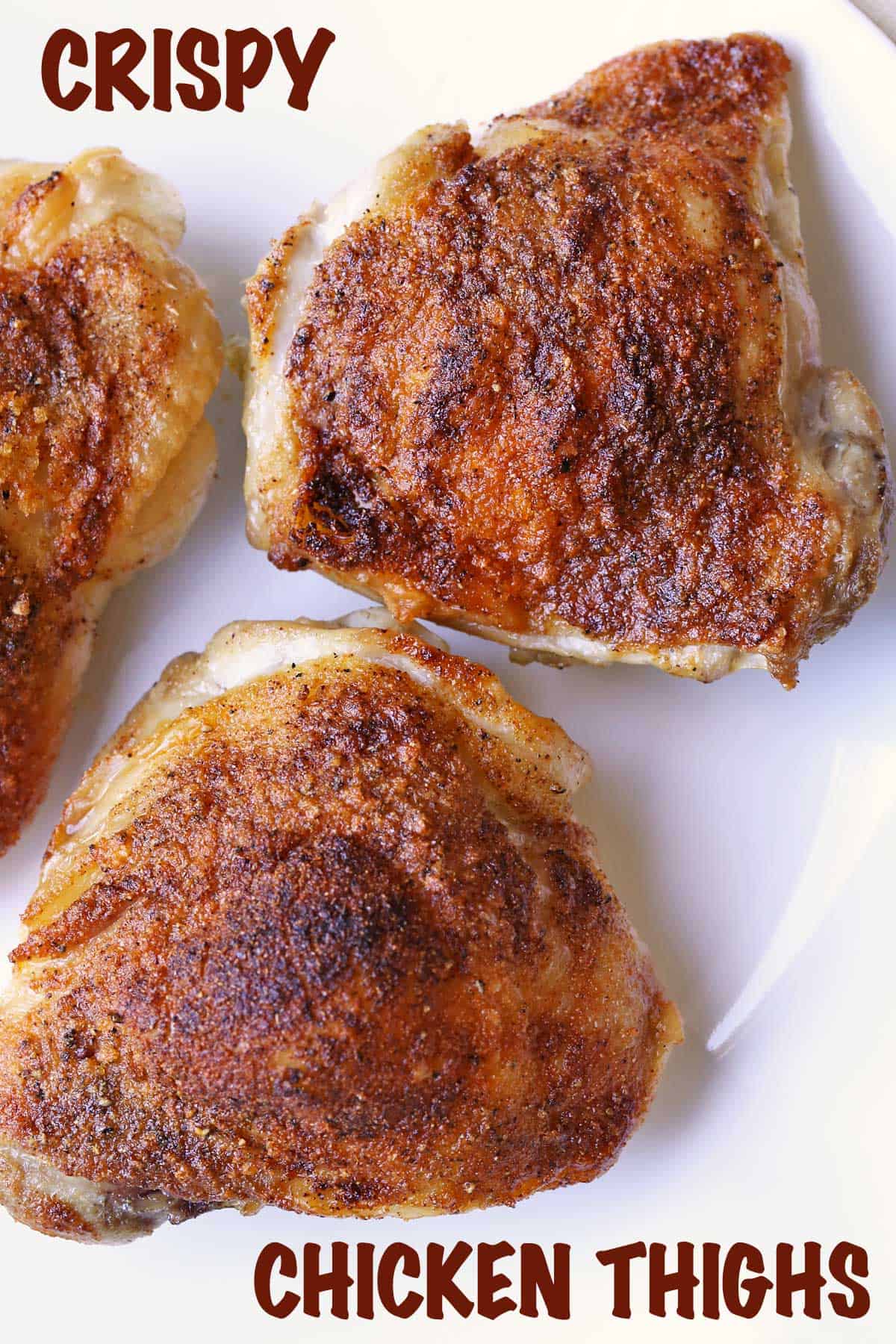 Baked chicken thighs with crispy skin, served on a white plate.