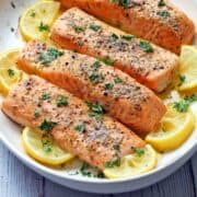 Baked salmon served on a platter with lemon slices.